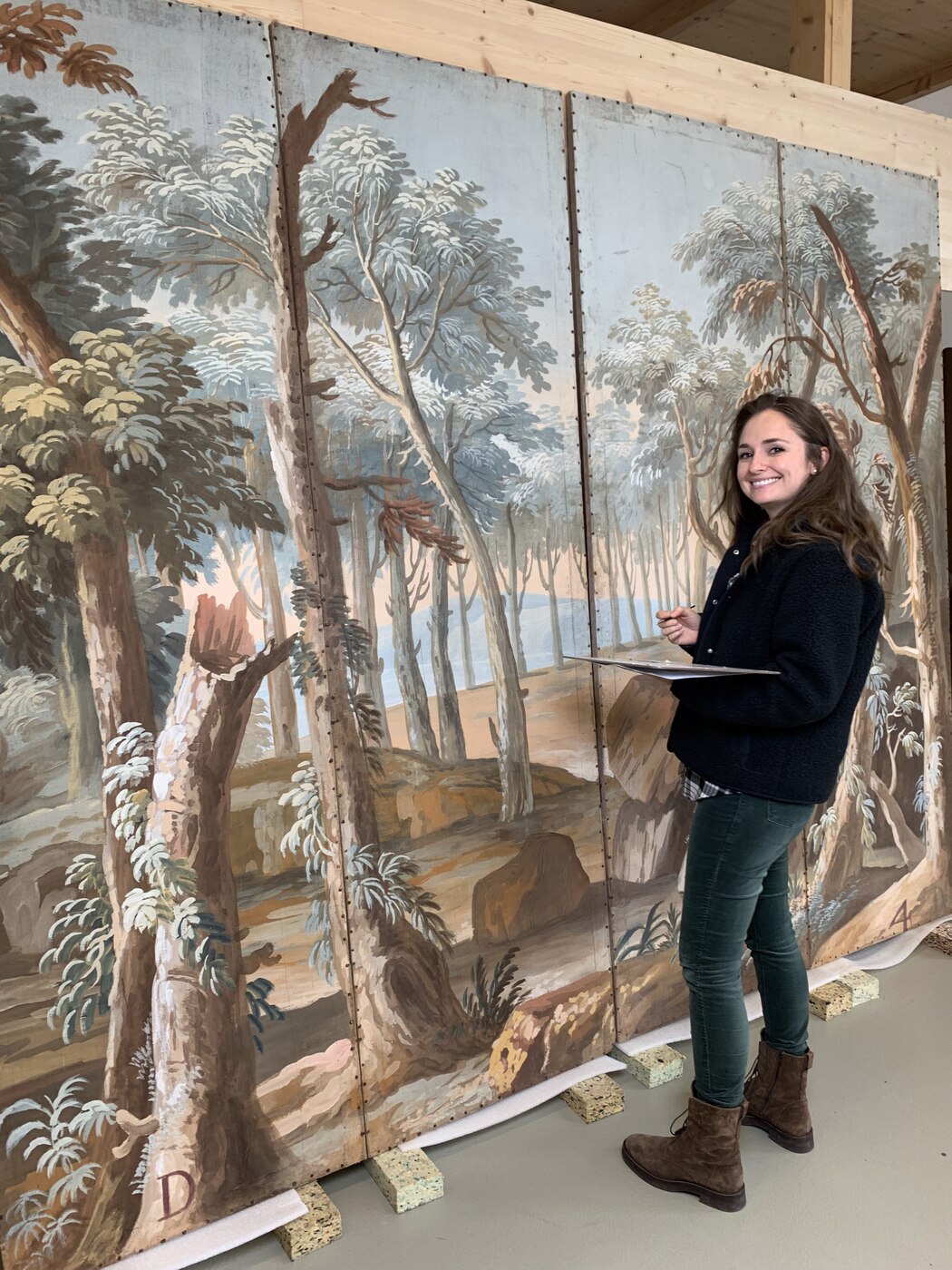 Portrait of the conservator in front of large painted theatre backdrops